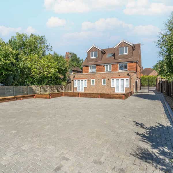 Car park area for four cars in the foreground, and the rear view of the building in the background.