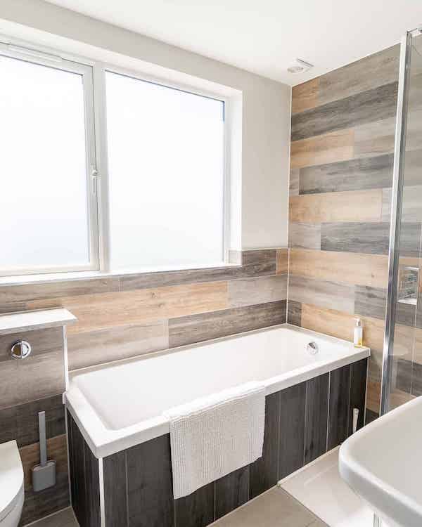 Bathroom with toilet on the left, separate bath and shower and a sink on the right of the image