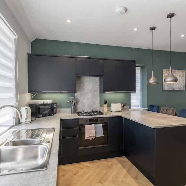 The kitchen area with sink on the left, kettle microwave and hob with oven, and a breakfast bar on the right.